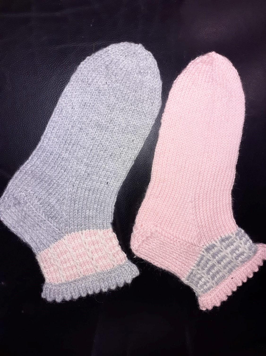 Anni Pitkämäen neulomat nirkkoreunasukat. Toinen sukka on nirkkoreunalta ja kärjestä harmaa ja sen varressa on vaaleanpunaisella ja valkoisella kerrosrivinousukuvio. Toisessa sukassa kärki ja nirkkoreuna vaaleanpunaisia, sekä kuviossa valkoista ja harmaata. 